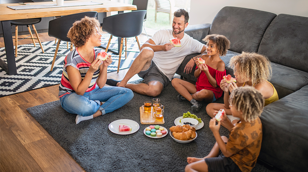 Multi ethnic family enjoying an improvised indoor picnic in their living room